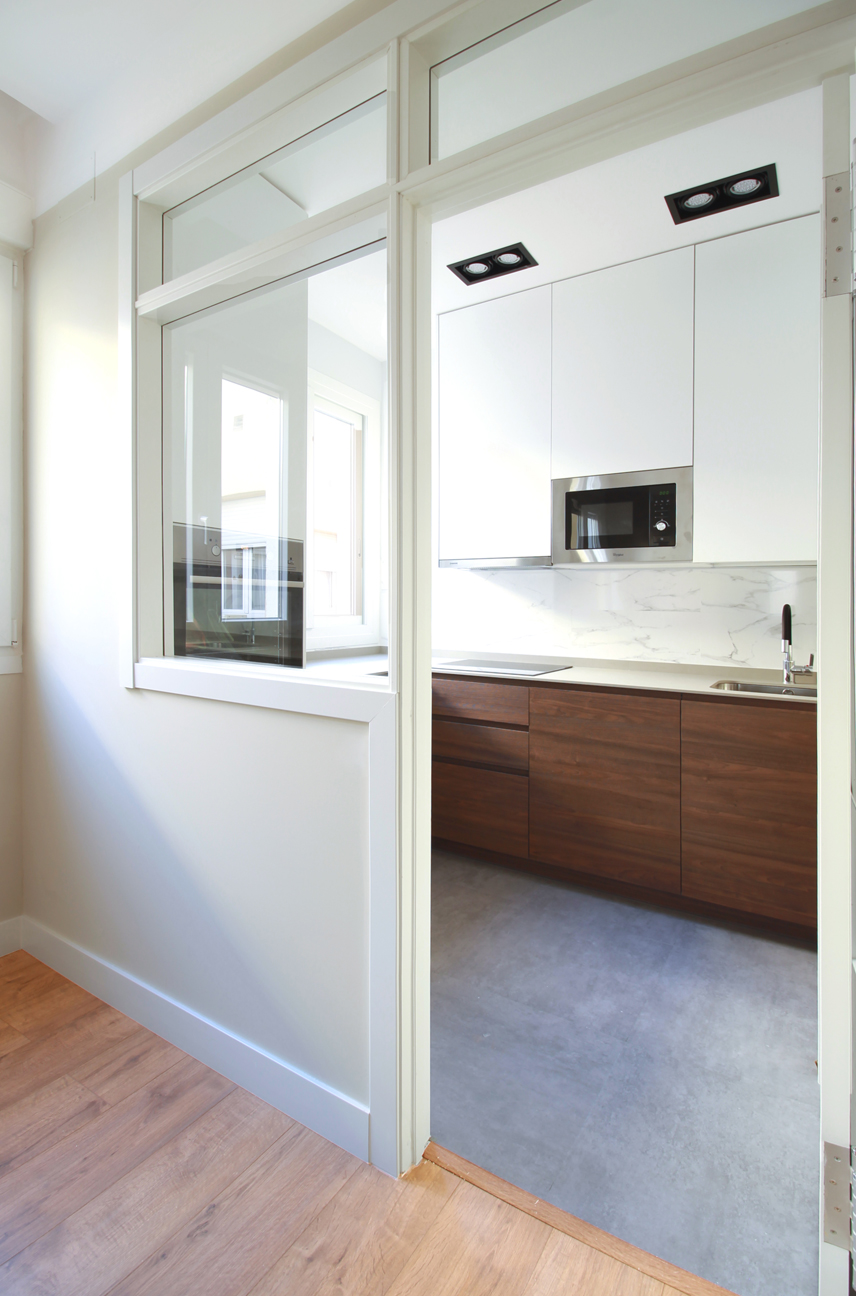 Reforma integral de vivienda. Acceso a cocina. Puerta y fijo en madera blanca con vidrio transparente